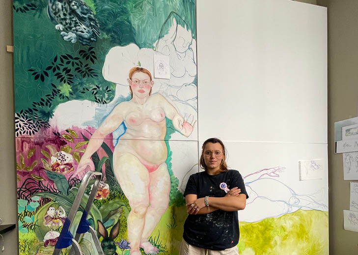 photographie d'une jeune femme debout devant une partie de peinture dans un atelier d'artiste