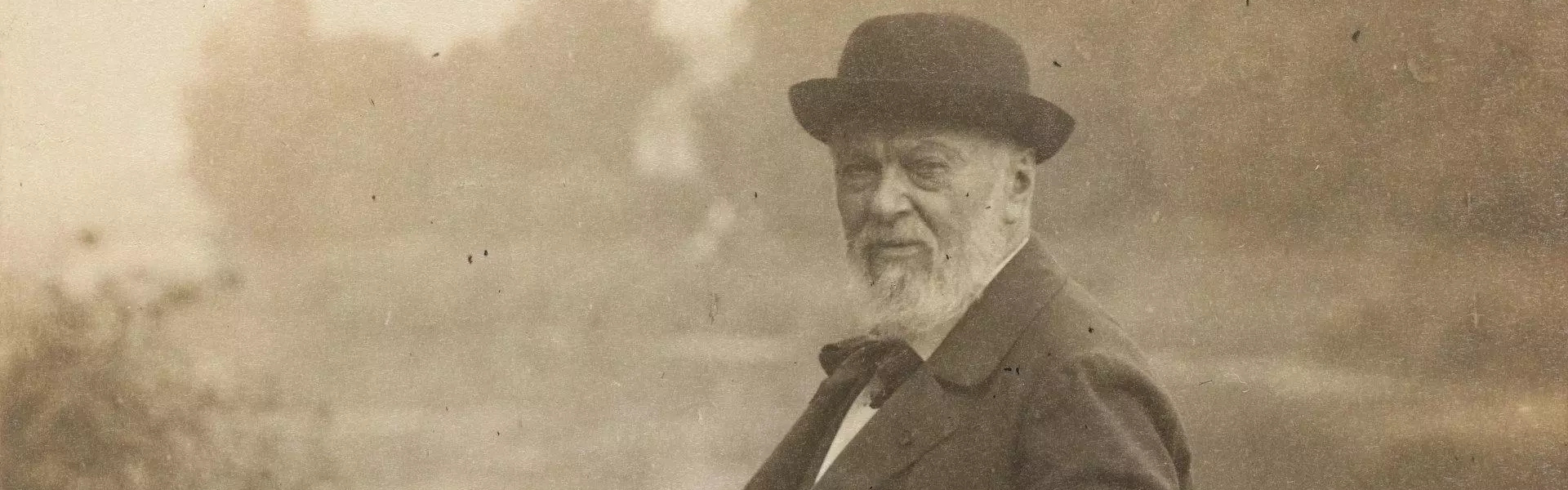 Photographie noire et blanche d'un vieil homme dans un paysage de campagne.