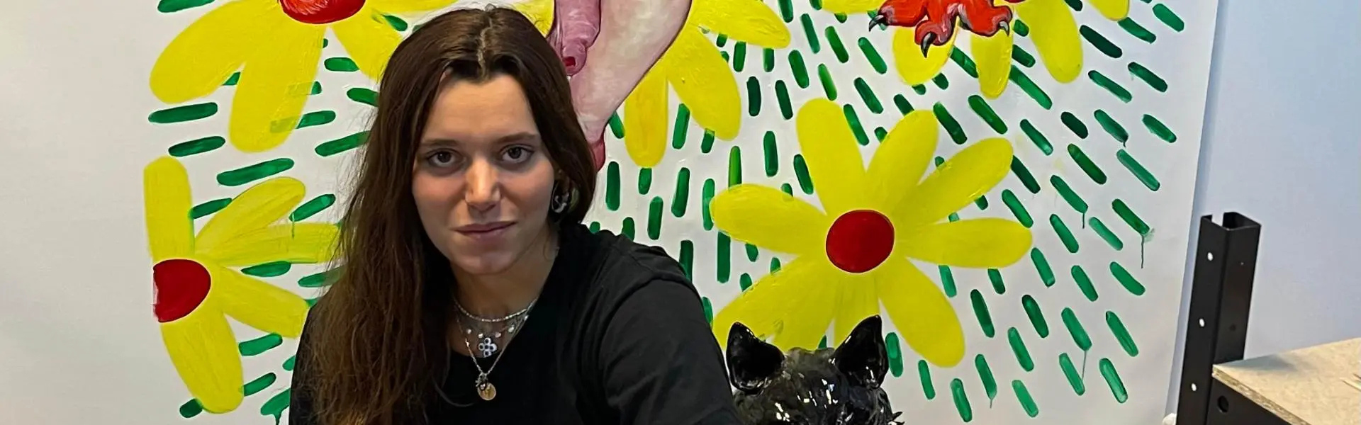 Photographie d'une jeune femme accroupie devant une peinture accrochée au mur 